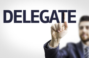Business man pointing to transparent board with text: Delegate